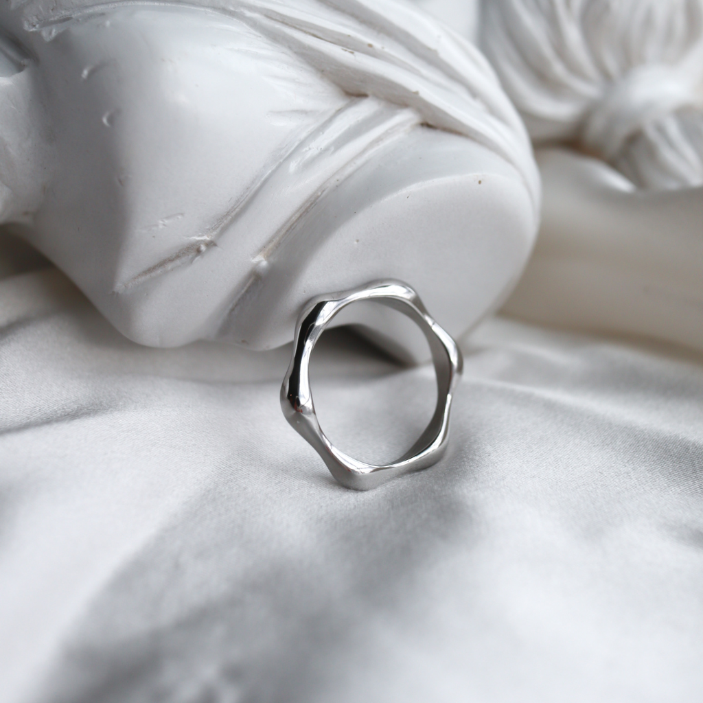 Silver geometric ring on a white fabric background