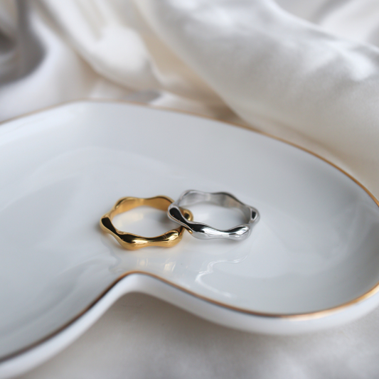 Two rings, one gold and one silver, on a white dish.