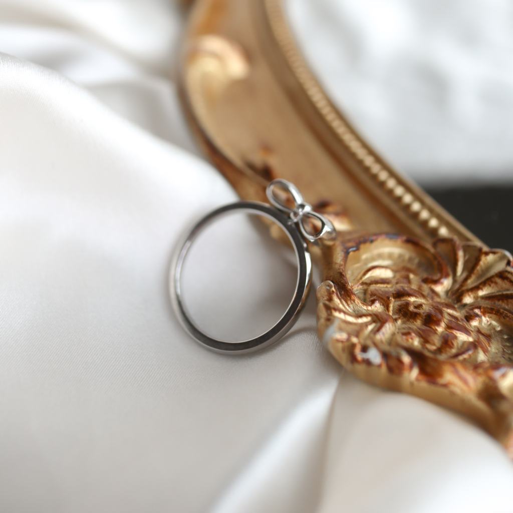 Silver ring on a decorative gold stand with a white background