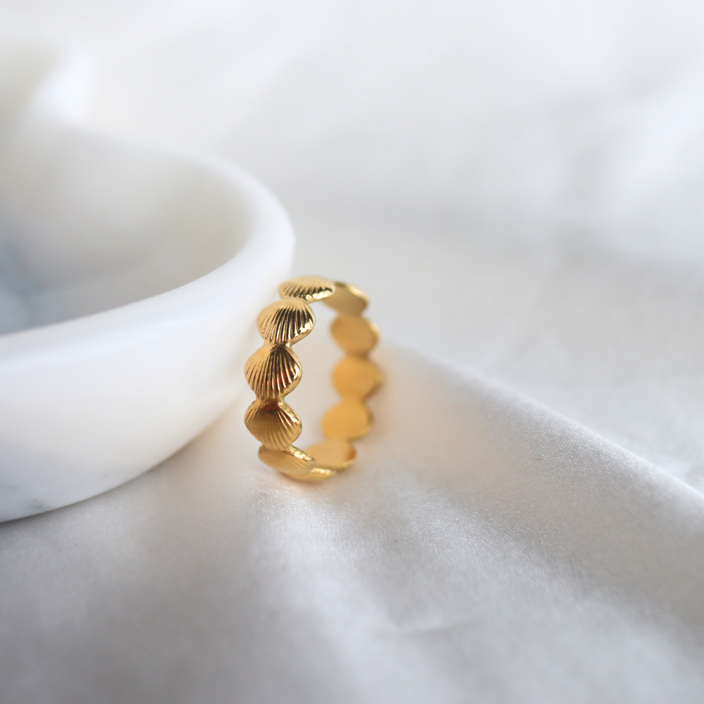 Gold ring with shell design on a white surface